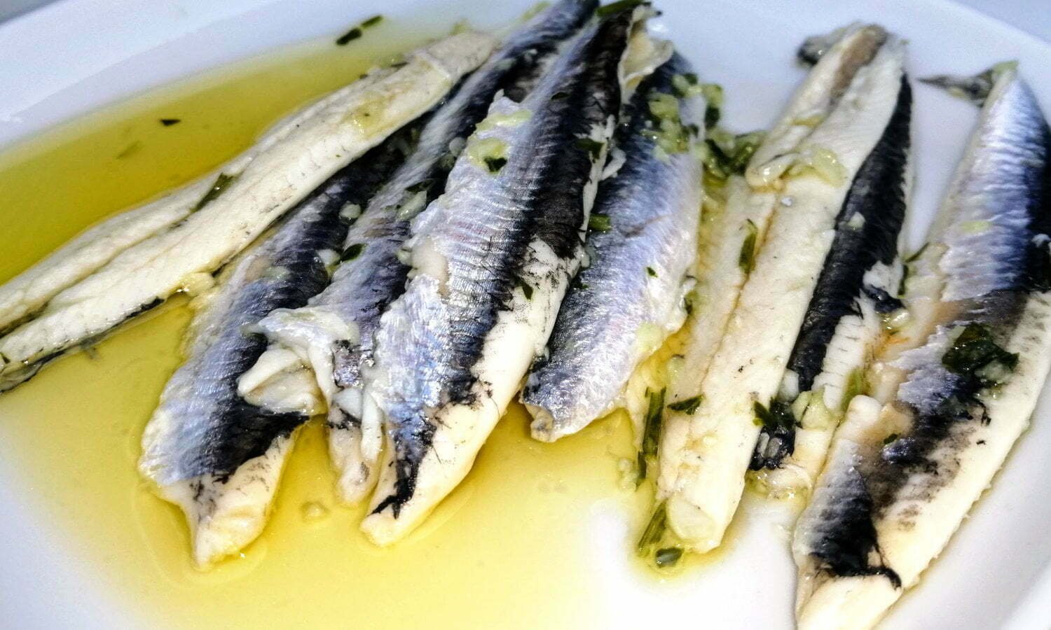 A plate of boquerones, spanish anchovies marinaded in vinegar, garlic, and parsley, and drizzled with extra virgin olive oil