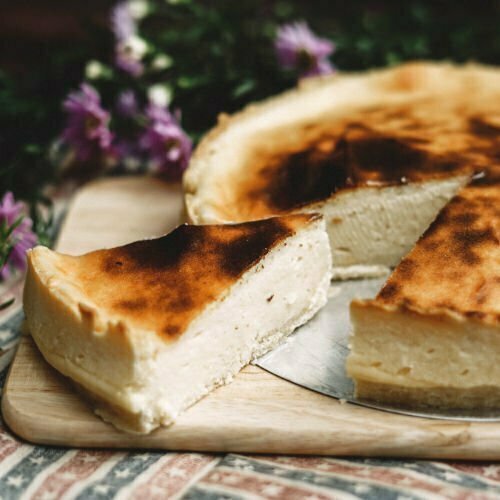 tarta de queso, traditional Spanish cheesecake dessert on a chopping board with a wedge cut away