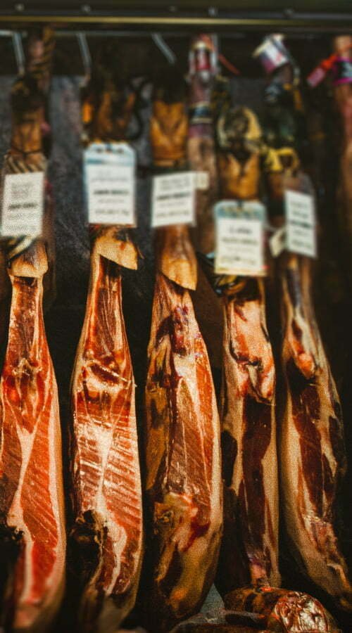 Legs of jamon hang in a butcher shop window