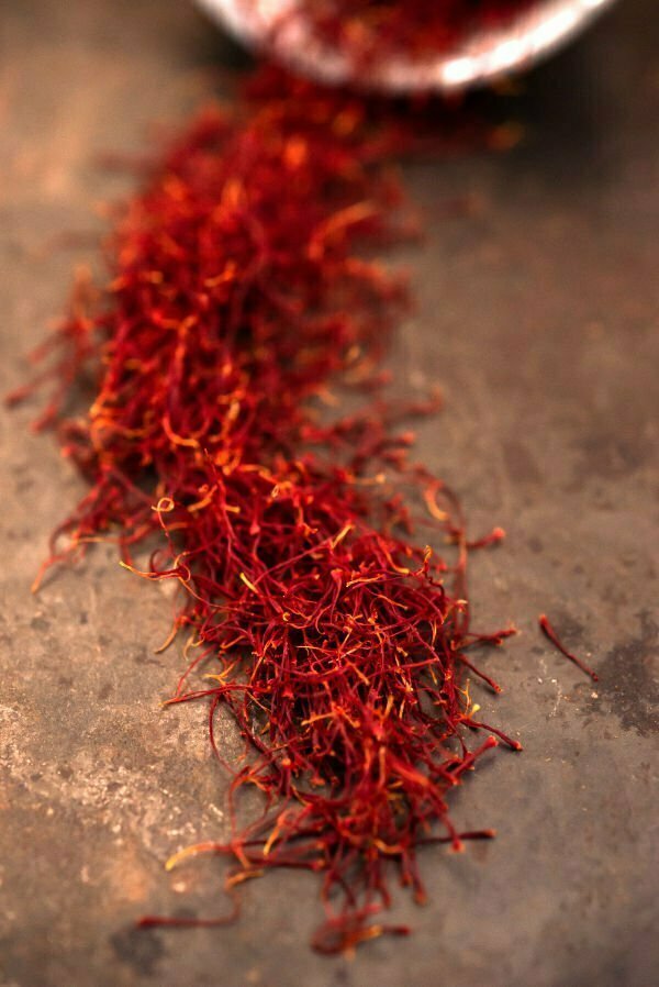 Long bright red threads of dried Saffron are laid out on a alrge wooden board
