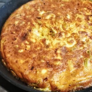 A alrge Asparagus tortilla sits. on a pan within a Spanish kitchen setting