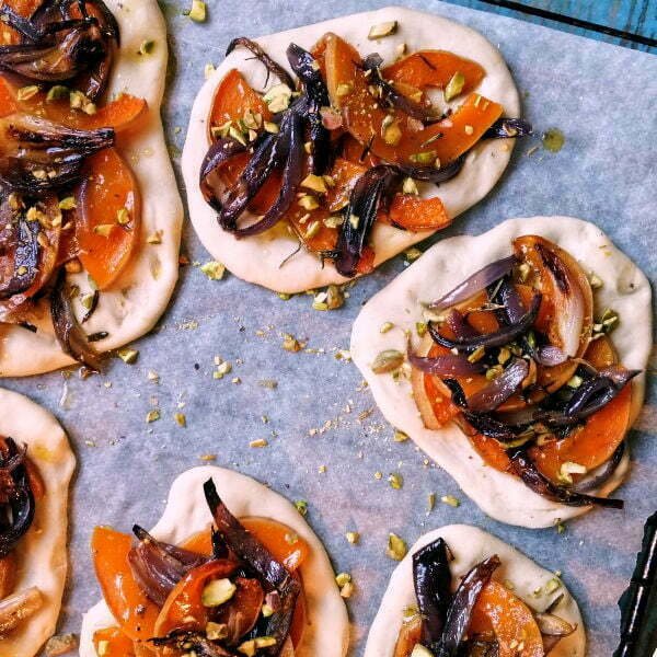 Pumpkin and caramelized onion Cocas sitting on an oven tray waiting to be baked