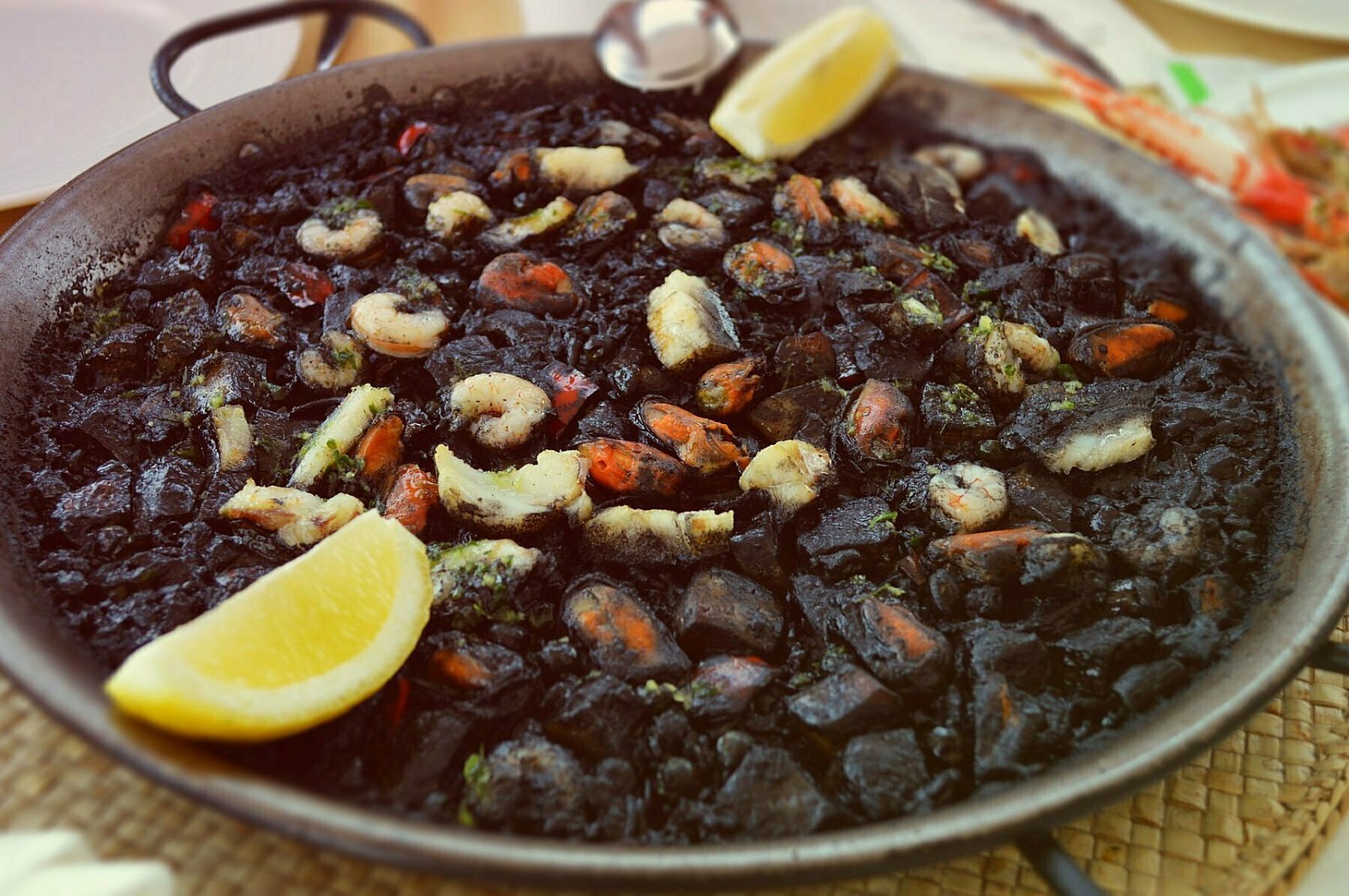 Paella negra sits in a large pan wait ing to be served. 