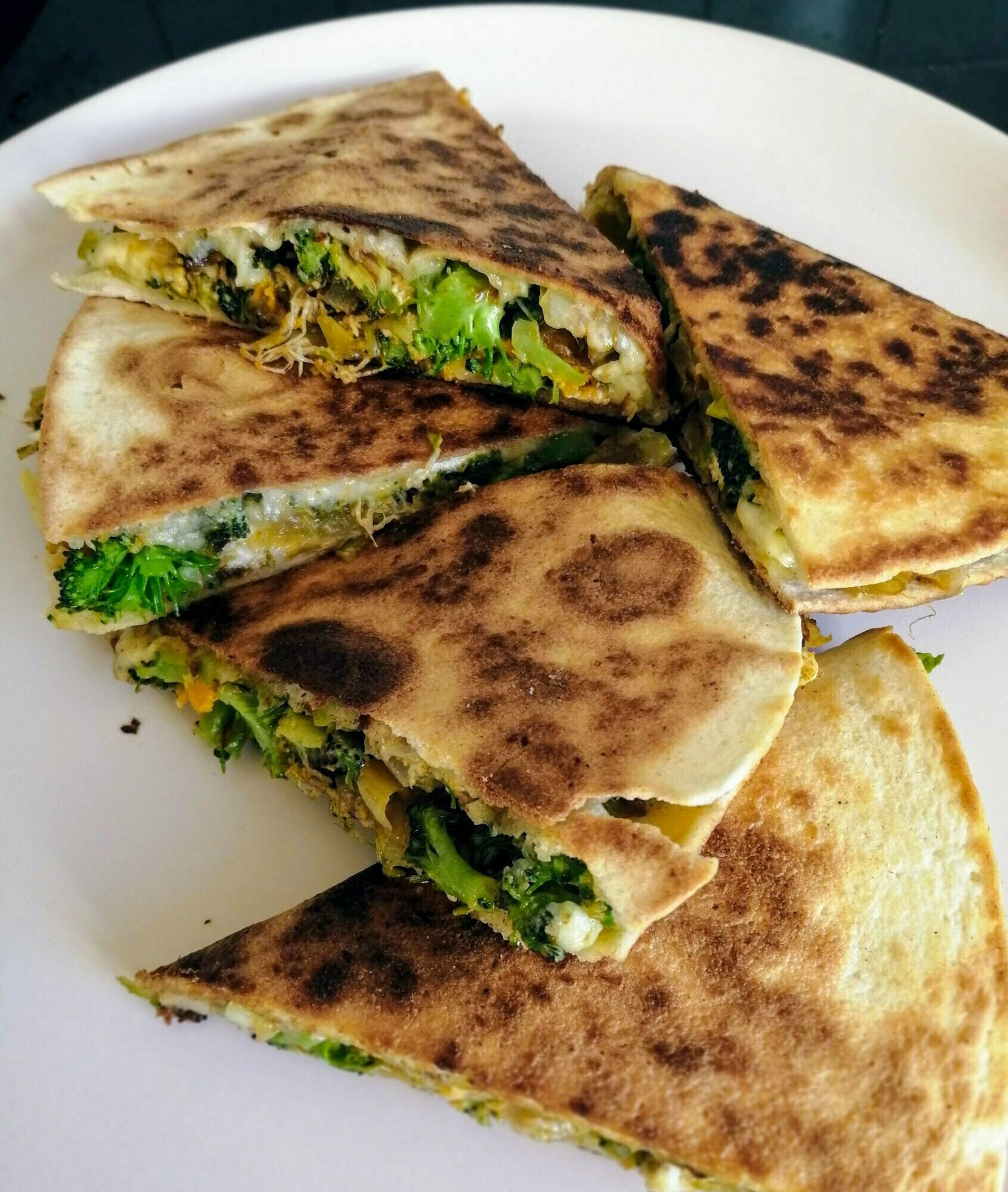 Leek, brocolli, and blue cheese quesadillas sit on a white plate