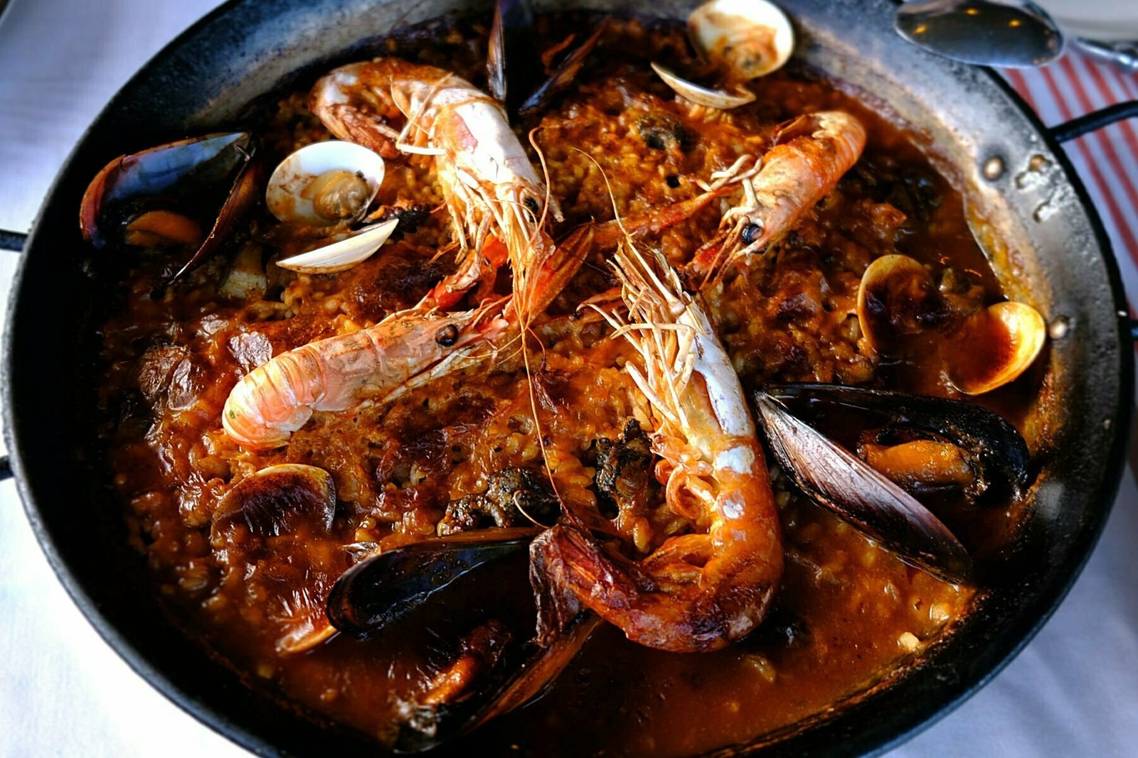 A large seafood paella sits on a table.