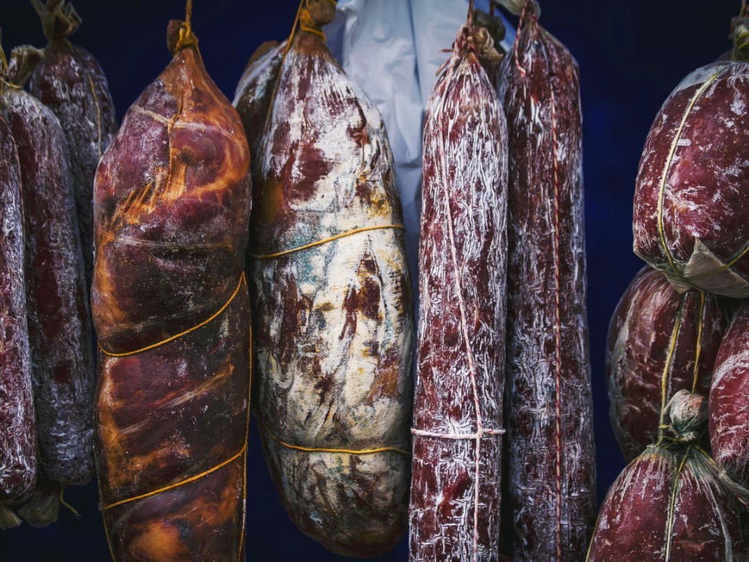 various types of Spanish chorizo hang in a storefront