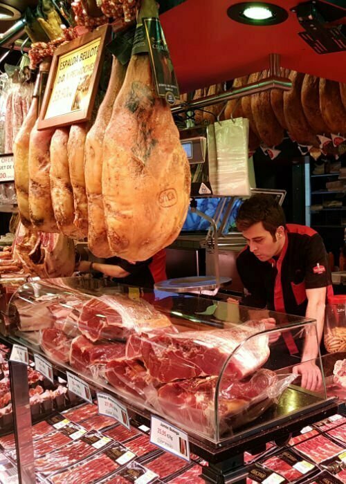 A meat vendor in a busy market stall prepares an order