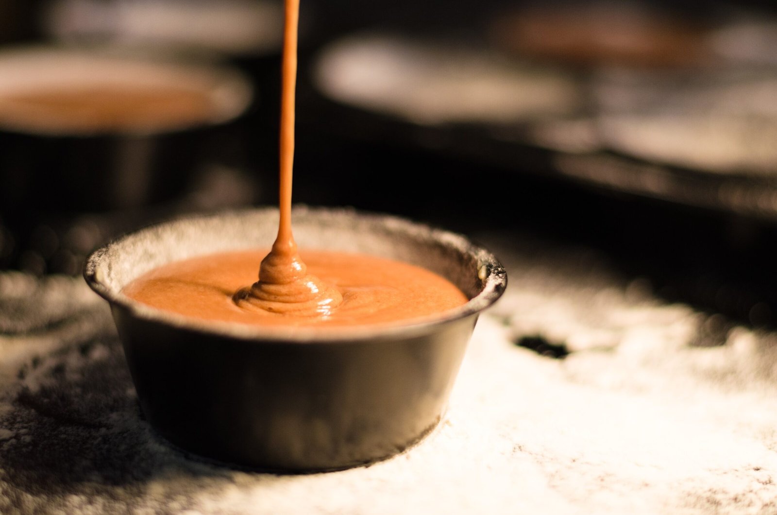 A earthenware pot is filled with caramel sauce in a rustic kitchen setting