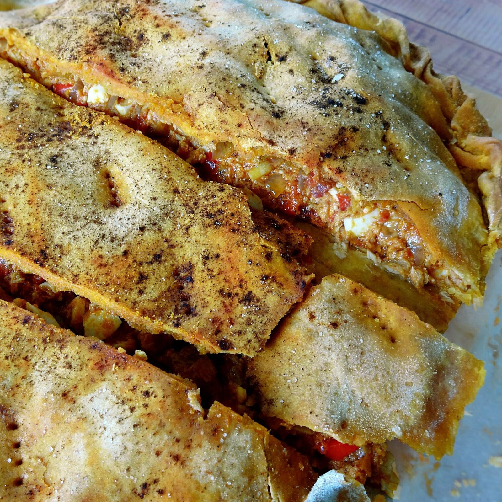 close up shot of an oven-baked empanada gallega with tuna and tomato filling