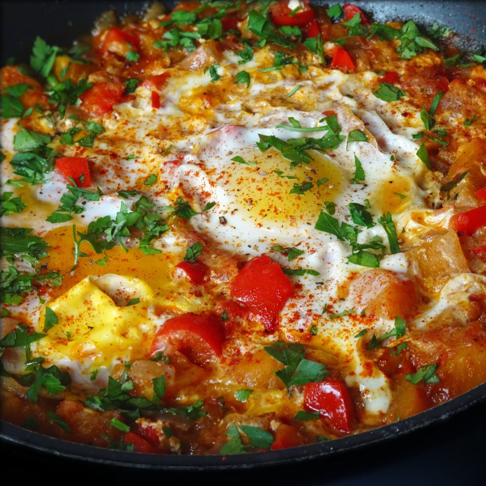 A frying pan of vegetable pisto with eggs sits on a counter top waiting to be served