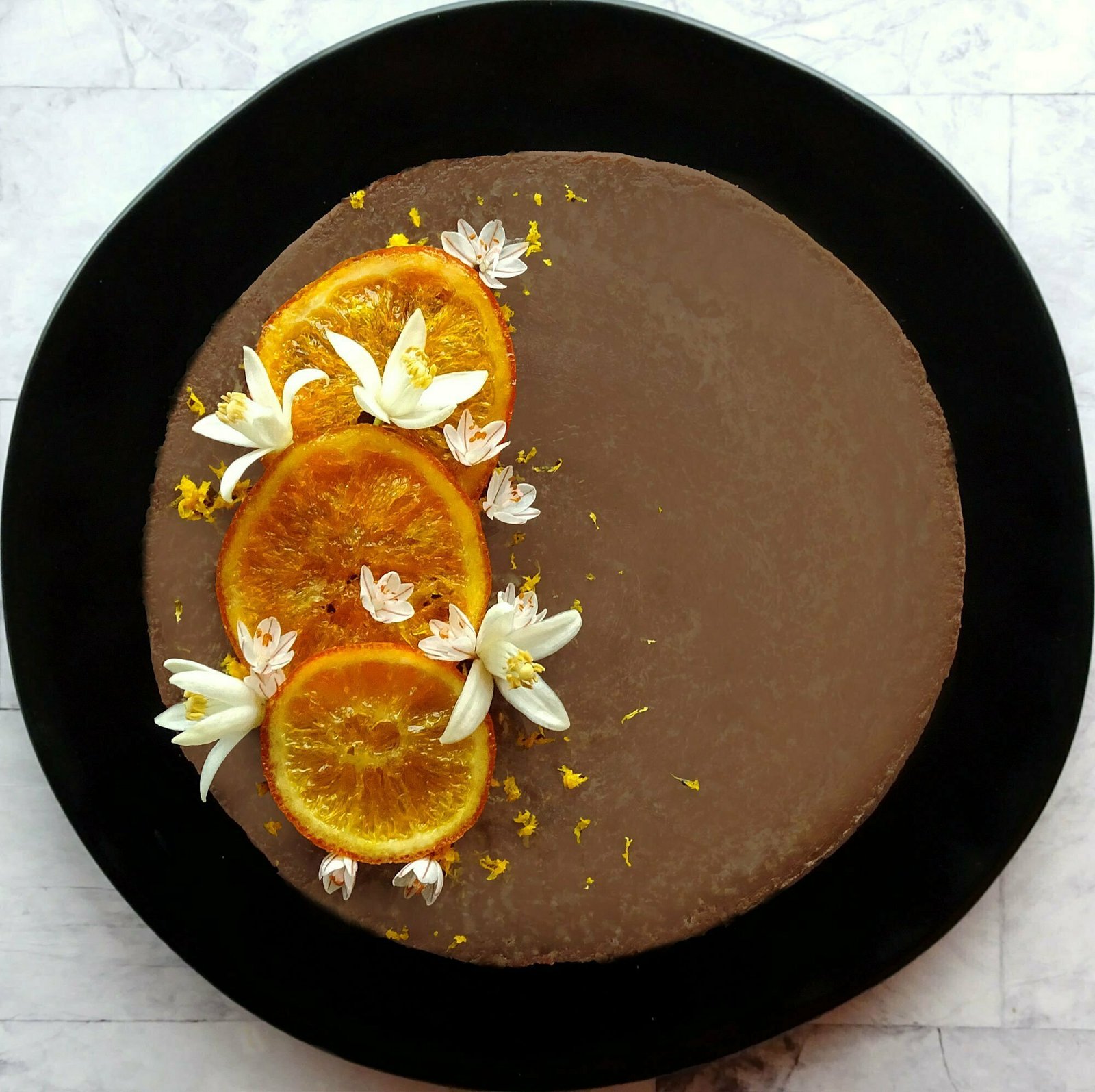 baked orange chocolate cheesecake is garnished with candied orange slices and some orange blossoms