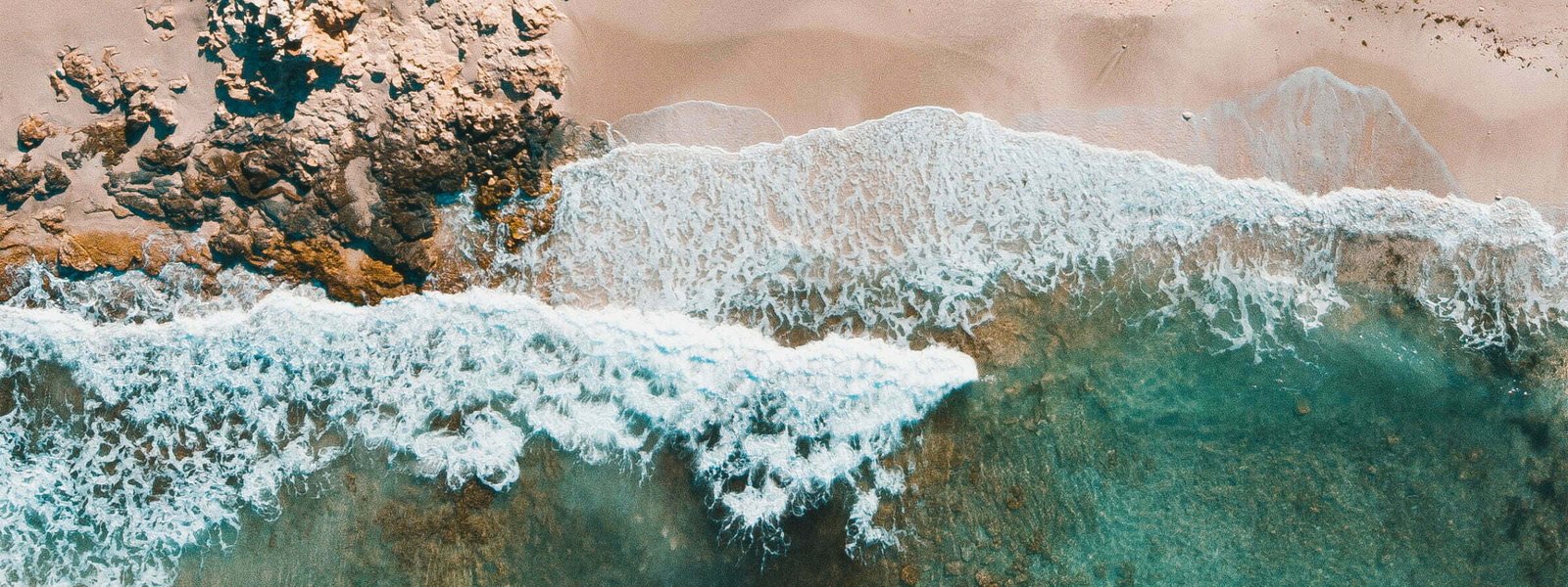 Blue waves crash onto a pink and white sand beach