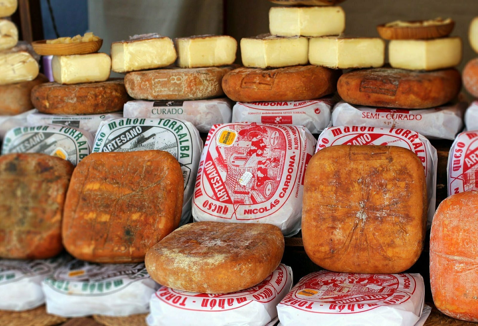 A market stall scene displaying wheels of queso de maron, a popular cheese from the Balearic Island of Menorca