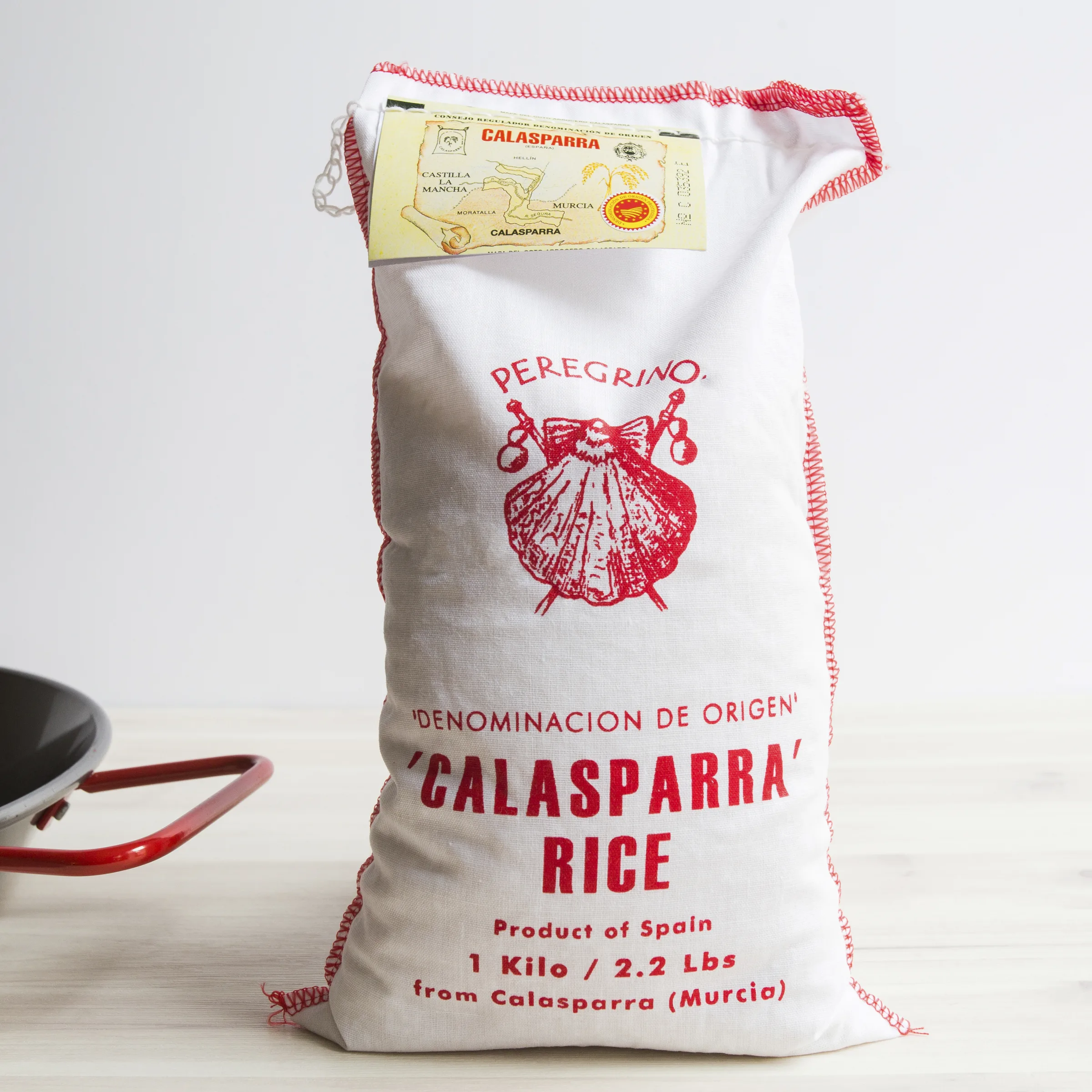 A large white hesson bag of caclasparra rice sits on a counter next to a paella pan