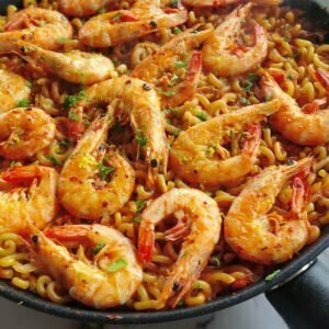 A large pan of fideua de marisco is topped with some golden shrimp