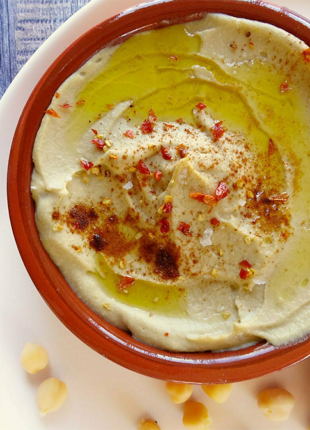 A earthenware dish sits filled with Mediterranean hummus