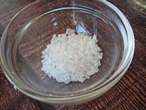 some coarse sea salt sits in a glass bowl