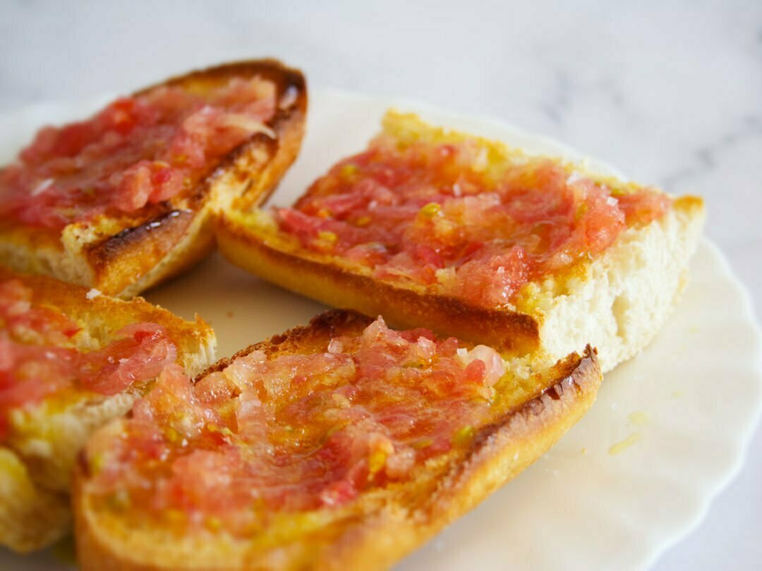 a large plate holds 4 slices of pan con tomate