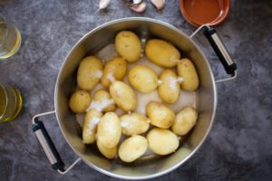 a large pot sits with potatoes and salt