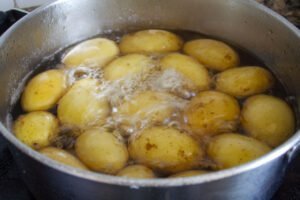 a pot of potatoes boils on a stove top
