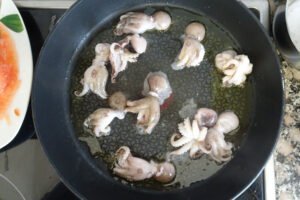 baby squid are being fried in a large frying pan