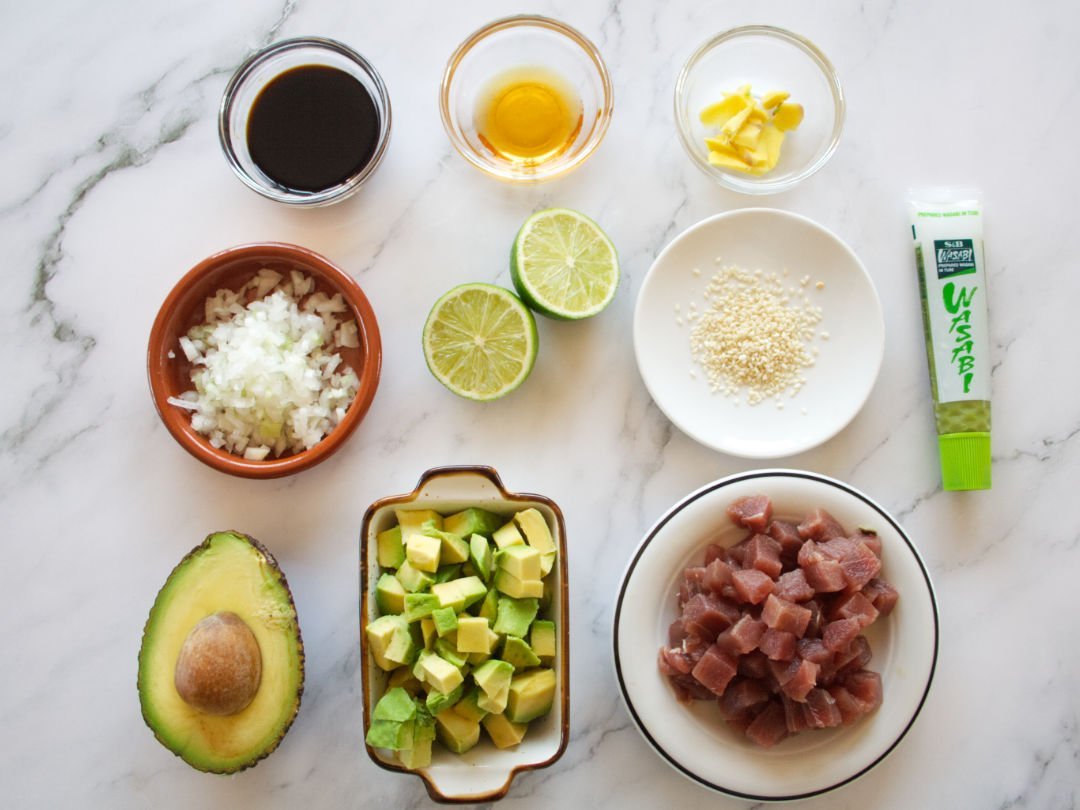 ingredients required for making tuna tartare are laid out on a white marble countertop