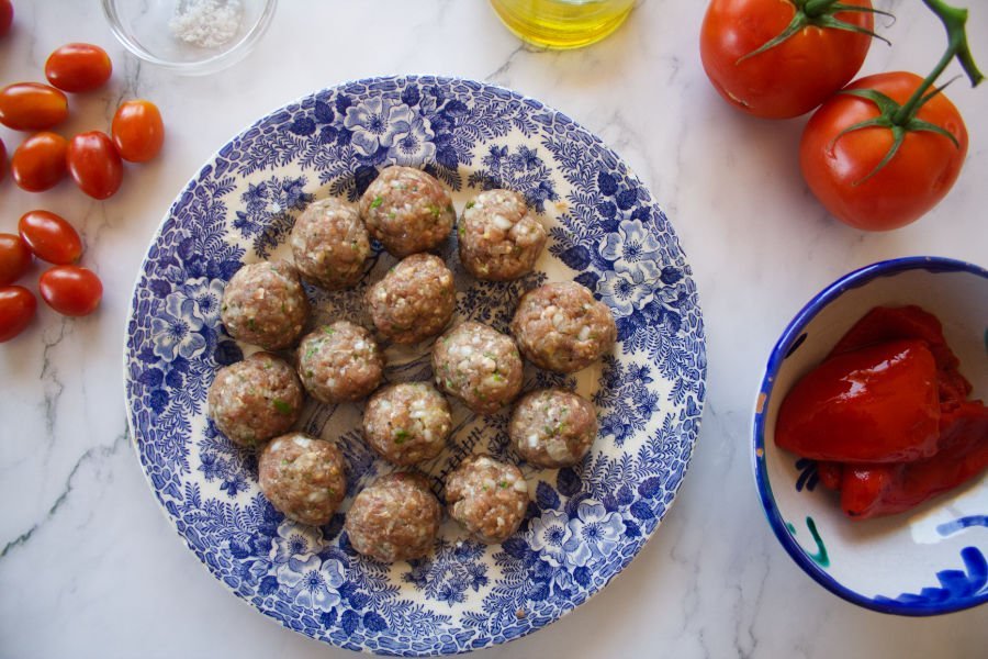 ingredients for mkaing albondigas sits on a white marble counter top