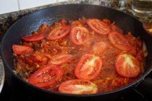 some tomato and red onion fry in a saucepan
