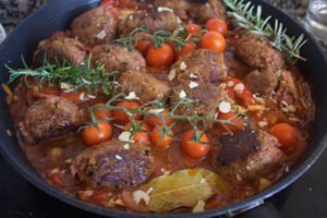 a large sauce pan is filled with a tomato. sofrito sauce and veggie meatballs
