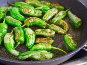 padron peppers frying in a pan