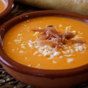 a small bowl of salmorejo is garnished with some diced egg and serrano ham.