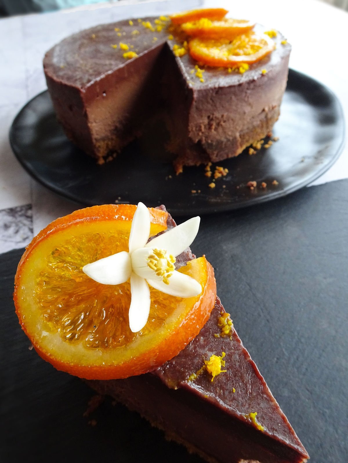 baked orange chocolate cheesecake is garnished with candied orange slices and some orange blossoms