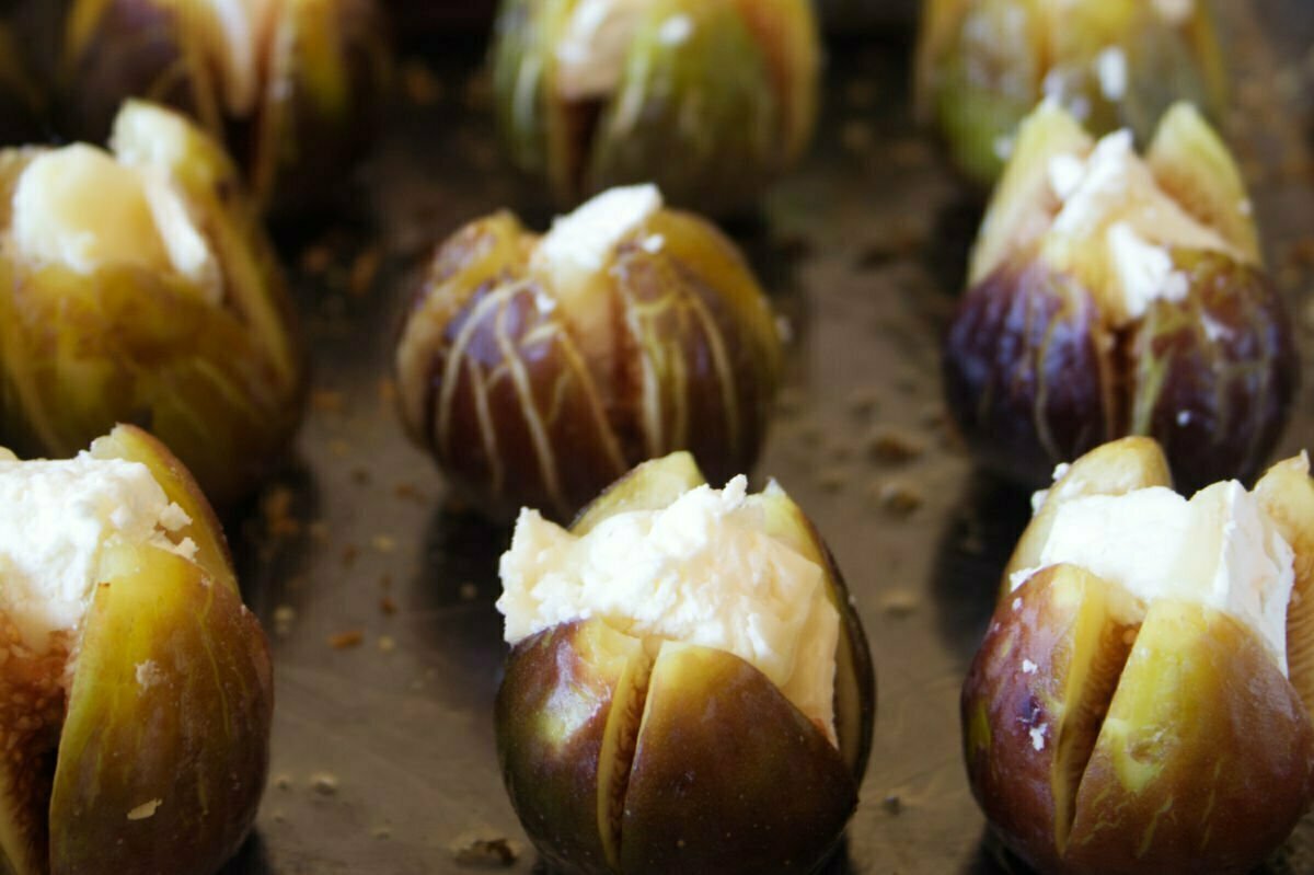 Figs are stuffed with goat's cheese in a oven tray.