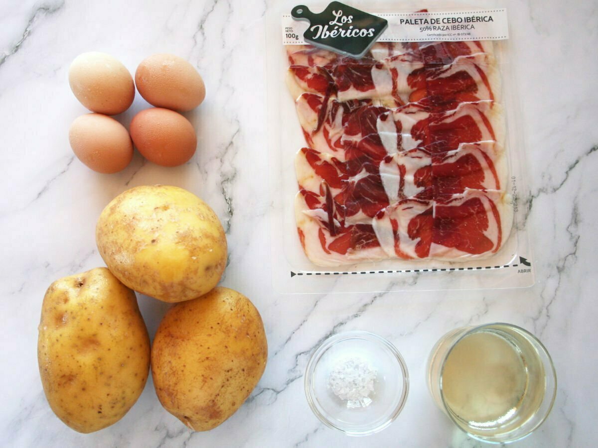 ingredients used for making huevos estrellados are laid out on a white marble counter