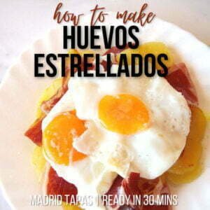 A plate of huevos estrellados sits with potatoes, eggs, and ham.