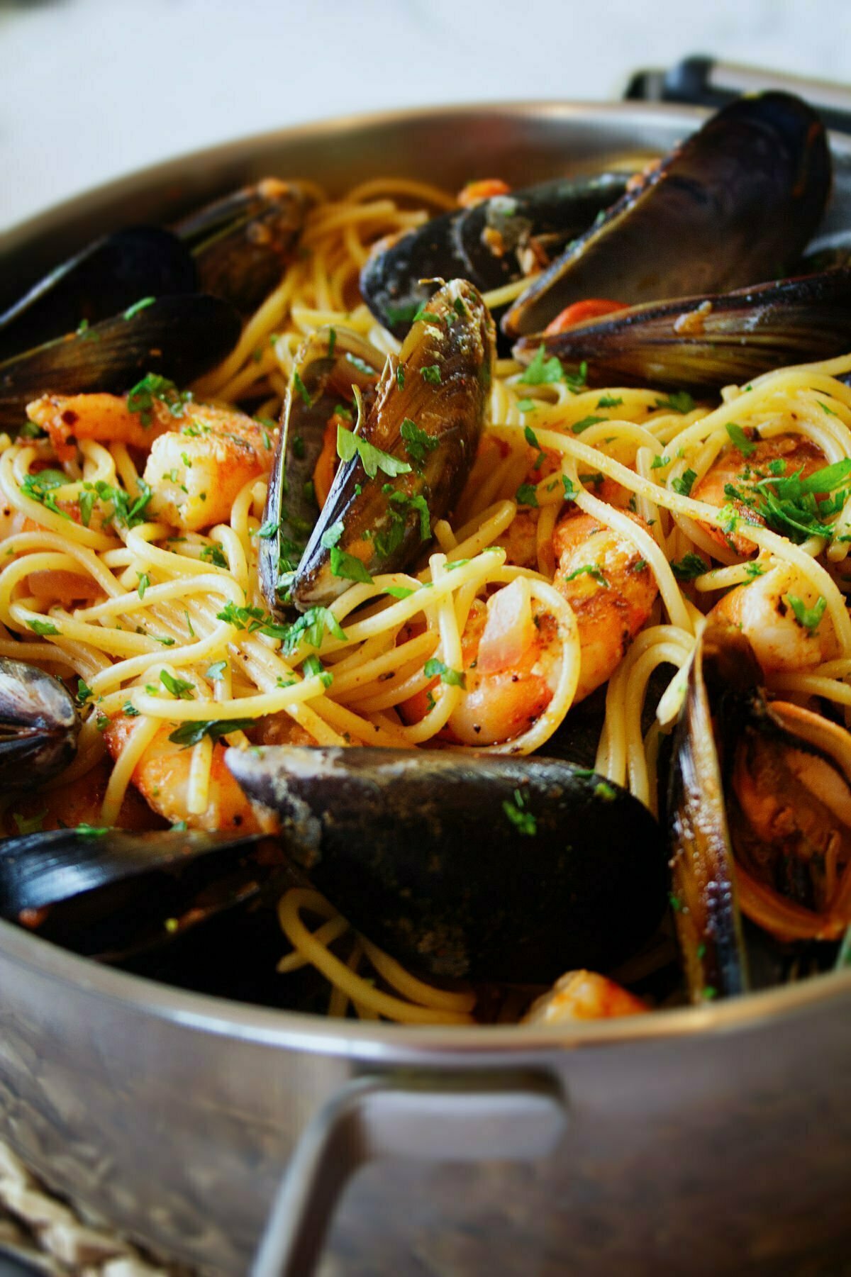 a large pot of shrimp and mussels pasta with some parsley garnish