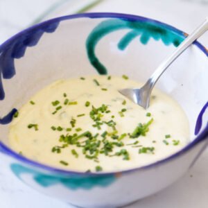 a small decorative bowl of healthy yogurt salad dressing with some chopped chives on top
