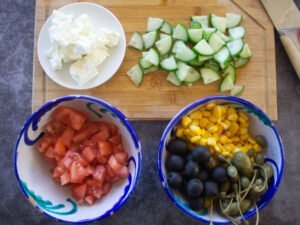 salad ingredients sit on a chopping board waiting to be prepared