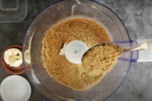 biscuits and some butter are added to a food processor and blended to breadcrumbs