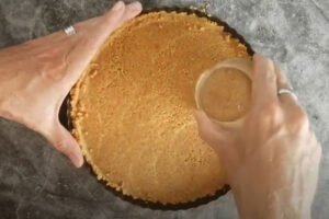 a glass is used to press down the biscuit base into the baking tin