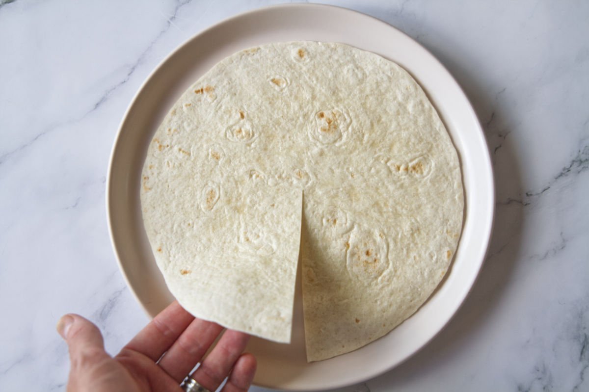 An organic flour tortilla sits with a small cut from 6 o'clock to the center. 