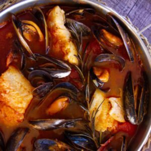 A pot of Mediterranean fish stew (Zarzuela de Mariscos) with mussels and fish in a broth