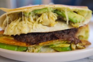A large breakfast tortilla sits loaded with veggies and cheese