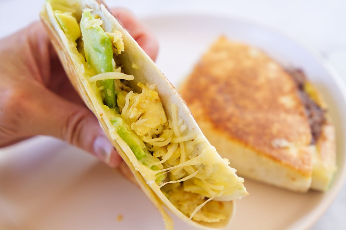 a cooked tortilla breakfast wrap with ccheese, avocado, and beans. 