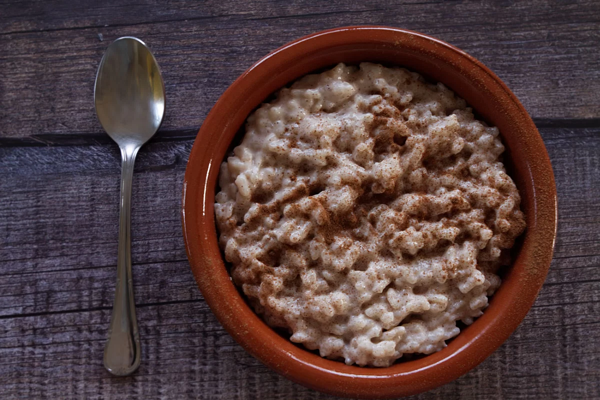 a small serving of arroz con leche is swerved beside a small dessert spoon