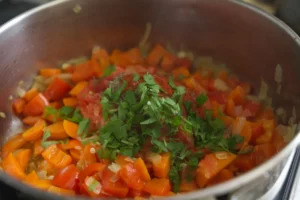 spices, and some fresh parsley are added to a pot of simmering vegetables