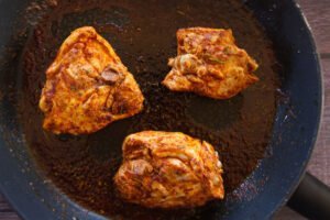 some chicken thighs sit in a frying pan