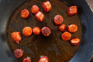 A pan with some cooked pieces of chorizo and oil