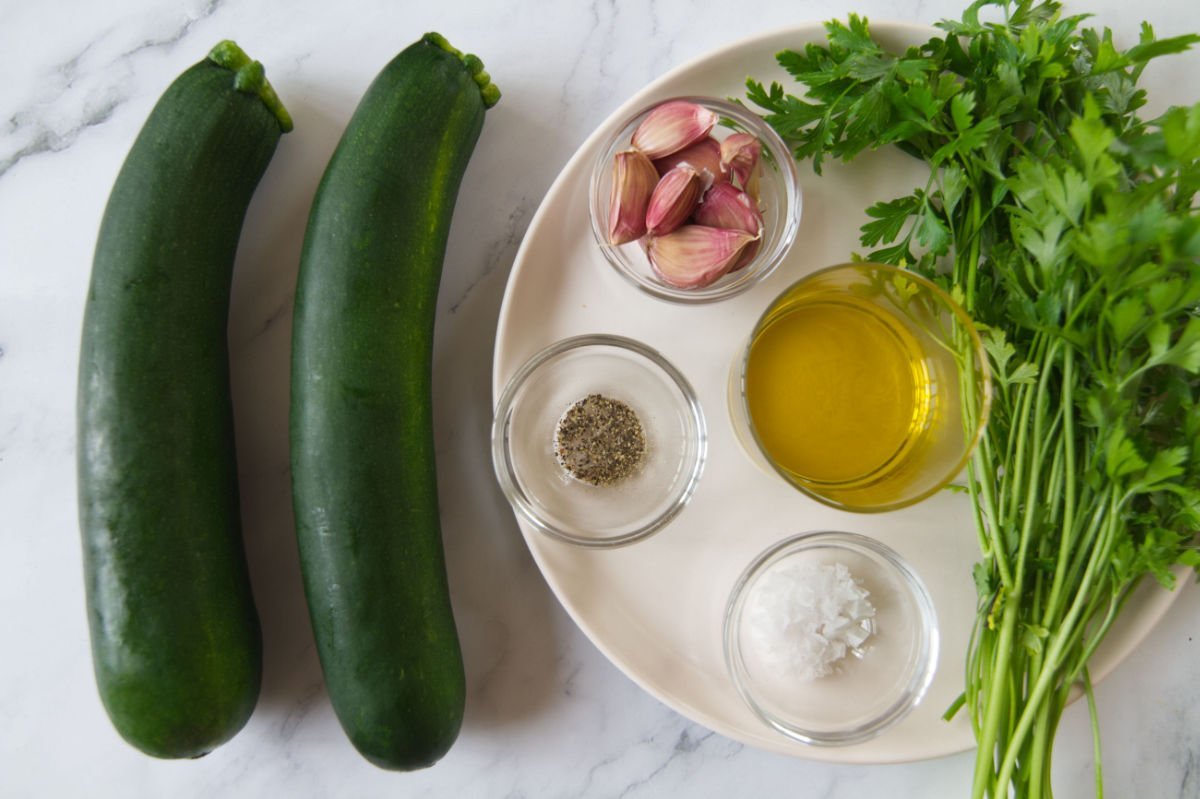 ingredients for making Spanish garlic zucchinis are laid out on a white granite worktop