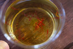 A few threads of saffron sit soaking in some white wine